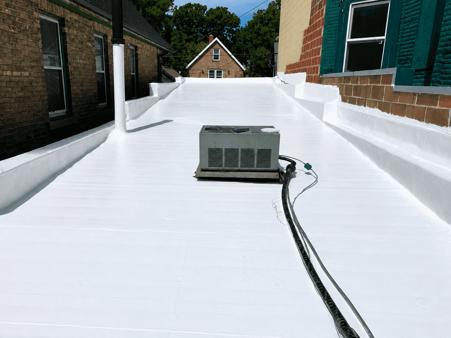 Commercial flat roof restored with a seamless white silicone roof coating and central HVAC unit
