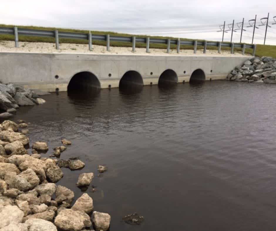 Concrete box culvert headwall drainage structure with multiple arched openings discharging water Concrete box culvert headwall drainage structure with multiple arched openings discharging water