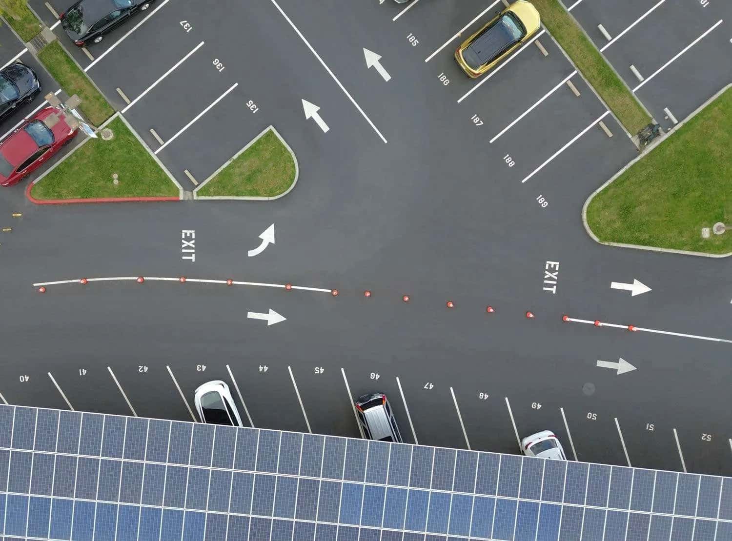Aerial view of a freshly sealcoated parking lot with white directional arrows and parking spaces Aerial view of a freshly sealcoated parking lot with white directional arrows and parking spaces