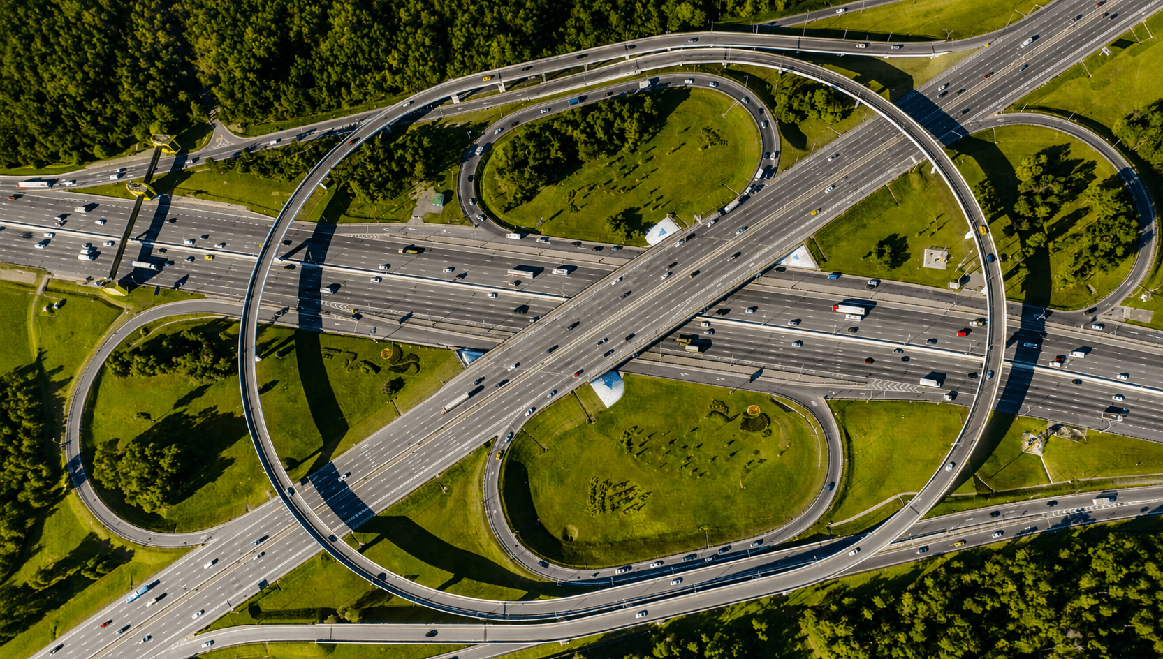 Civil & Roadway Construction Aerial drone shot of a modern complex urban highway interchange surrounded by city trees