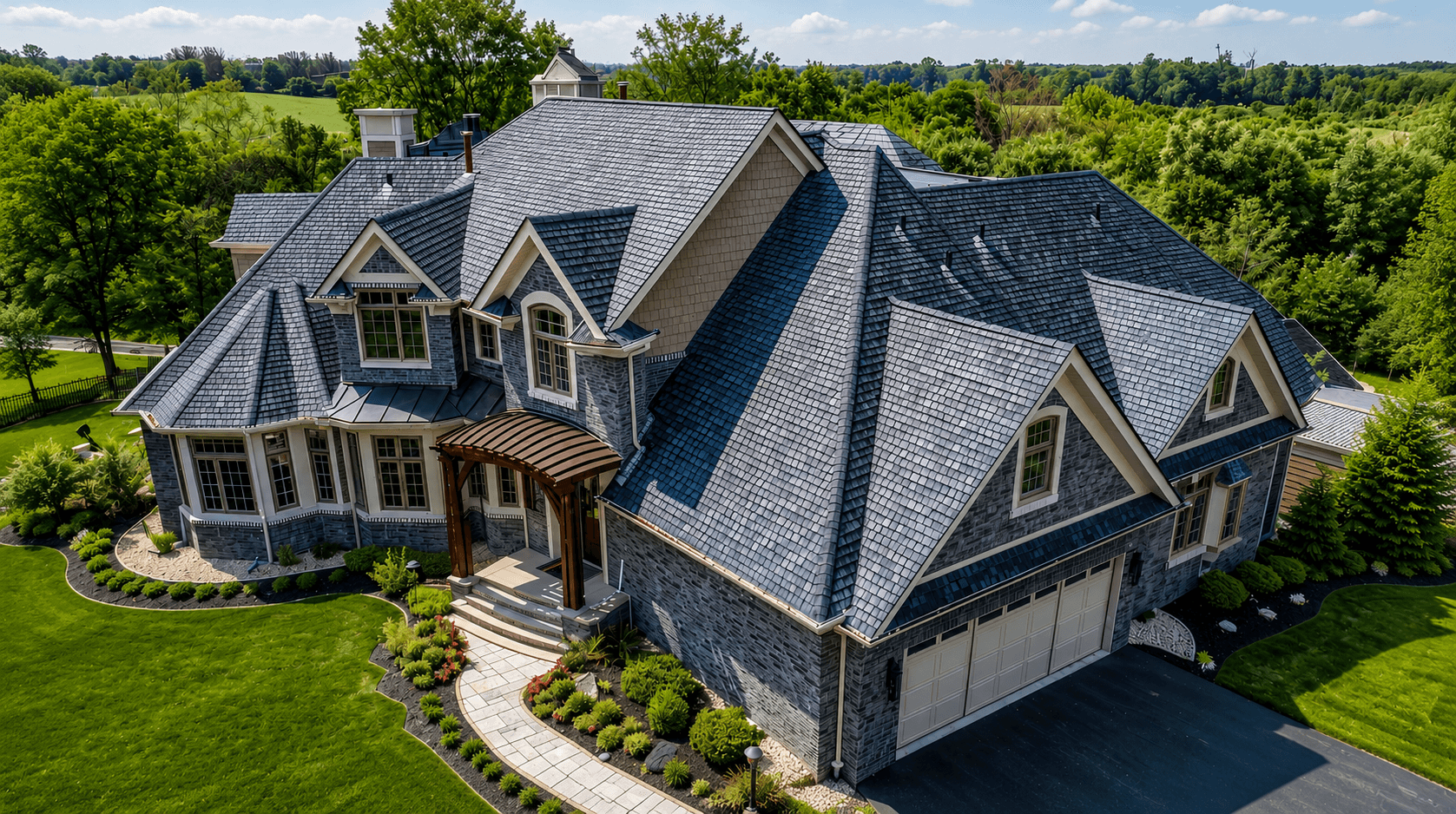 Patriot Asphalt & Construction — Licensed Contractor Albuquerque NM High-angle aerial view of a luxury residential home featuring a complex dark slate tile roof and manicured lawn